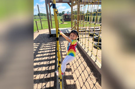 young asian girl climbing on ropes at the park