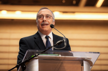 a man is standing in front of a podium with a microphone talking out to an audience 