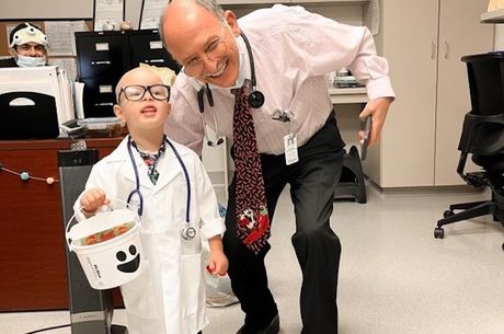 Dr. Khearapour bent down next to his pediatric cancer patient who is dressed up as a doctor