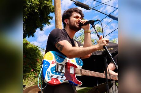 Brandon singing at a microphone with a multicolored guitar strapped over his shoulder
