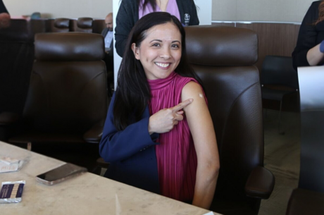 LLUH CFO Angela Lalas is all smiles after getting her flu vaccine A women smiles at the camera and points to a bandaid on her arm