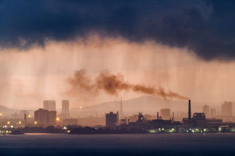 Dramatic sunrise and rain over industrial area - stock photo