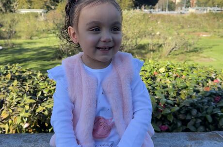Alaia Pacheco sitting on a bench and smiling while looking off camera