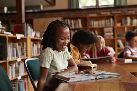 Happy girl reading book in library
