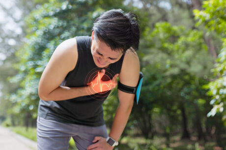 young man in park bends down by roadside and suffers from chest pain 