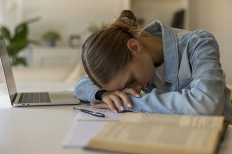 Exhausted Young Student Girl Sleeping on Desk While Studying at Home