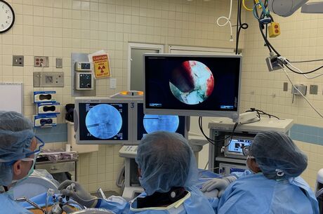 Three doctors in an operating room looking at the screen
