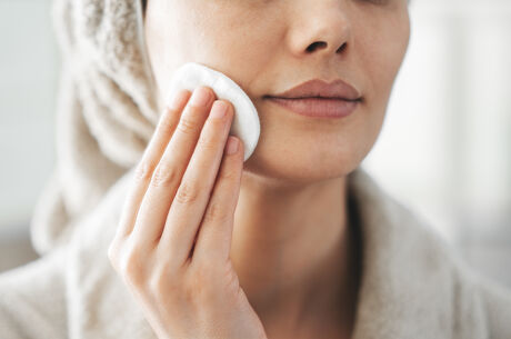 Woman swiping cotton pad across skin