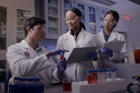 a group of people are in a medical setting looking over a vile of medication 