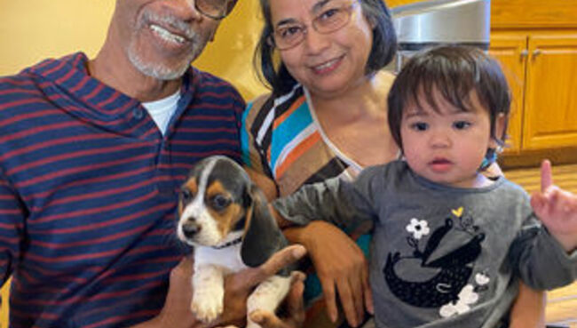 family smiling holding dog