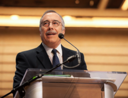 a man is standing in front of a podium with a microphone talking out to an audience 