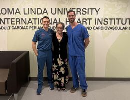 a woman poses with two men beside her all smiling 