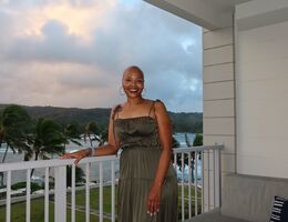 Sonja Loadholt stands on balcony overlooking beach and palm trees