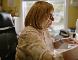 A woman is sitting in a chair using a sewing machine