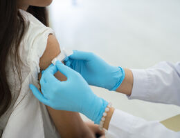 Doctor applies bandage to girl&#039;s arm following an immunization