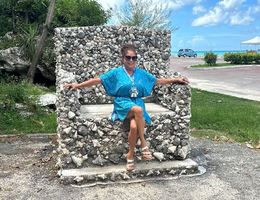 Brenda Roper sits on cobblestone throne or chair in a blue dress and sunglasses