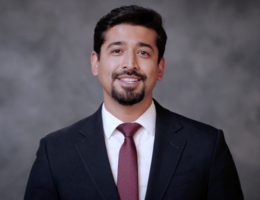 A man in a suit with a beard is smiling