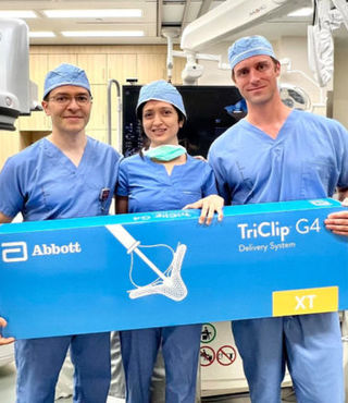 3 doctors holding large box of TriClips for new heart proceedure