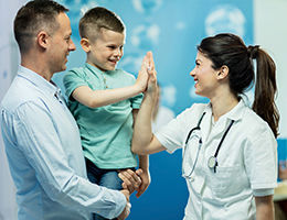 doctor high fiving child patient in dad's arms