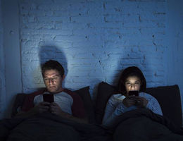 Man & woman in bed looking at their phones