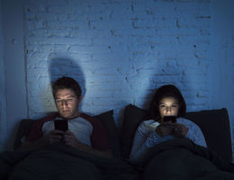 couple looking at there tablets before bed