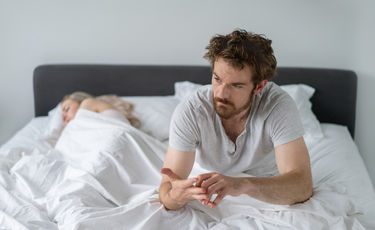 Man unable to fall asleep, laying in a bed