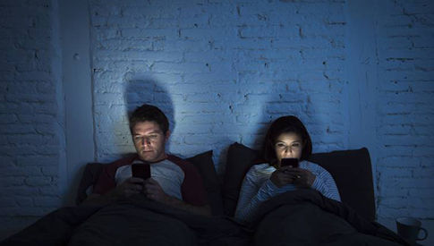 Man & Woman in bed looking at their phones