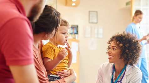 Female doctor kneeling to talk with parents of small child